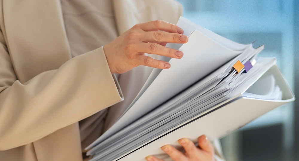 anos de un empleado organizando una gran cantidad de carpetas y documentos físicos de la empresa.